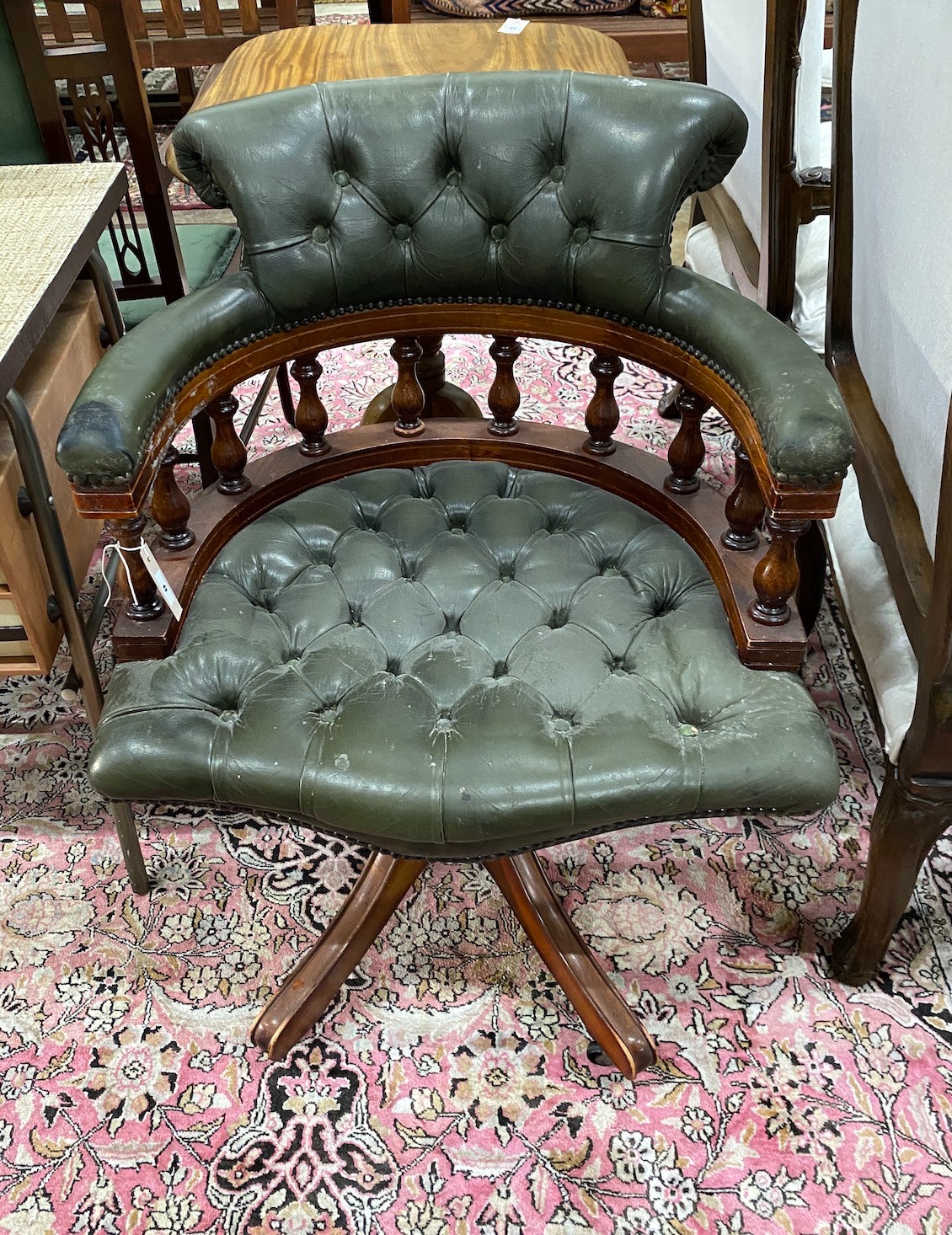 A reproduction buttoned green leather mahogany swivel desk chair, width 62cm, depth 56cm, height 85cm